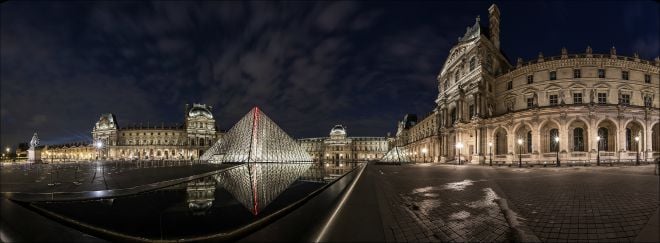 The Louvre museum and I. M. Pei's glass pyramid lit up at night. Image by Adrien Sifre.