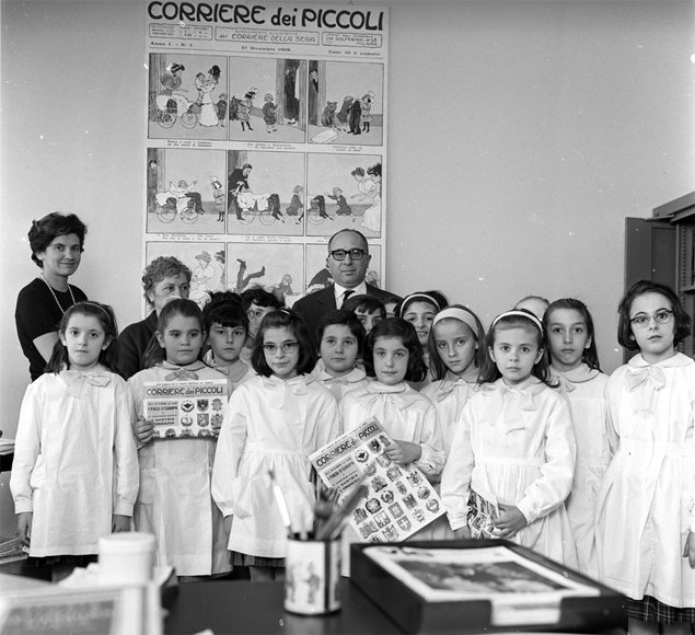 Like this picture, my sisters and I wore white uniforms called Grembiule to school every day. The best children received a red sash — in two years I never got one.