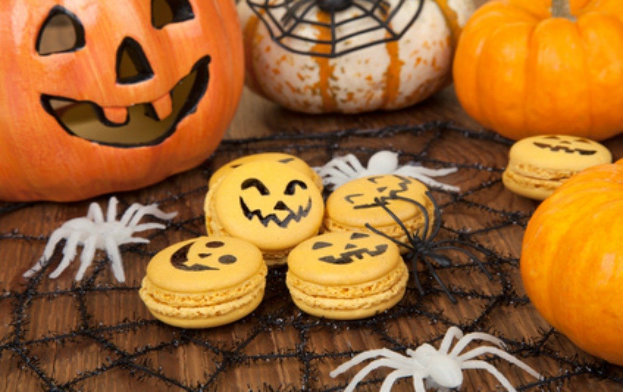 Closeup of Halloween decor with French pumpkin macaroons and assorted pumpkins.